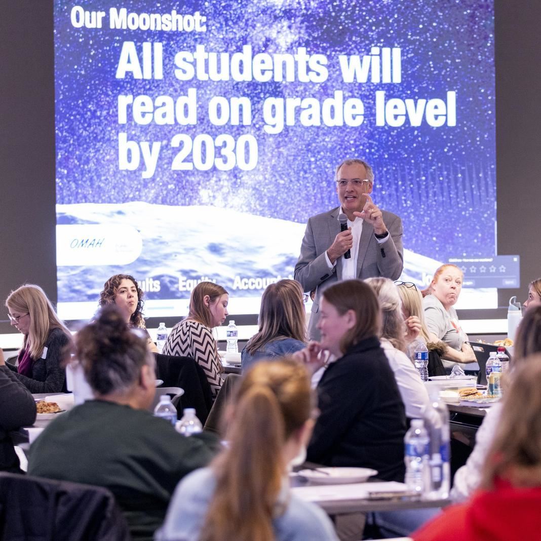 Superintendent Matthew Ray presents to a group of teachers in front of a slide with the moonshot goa